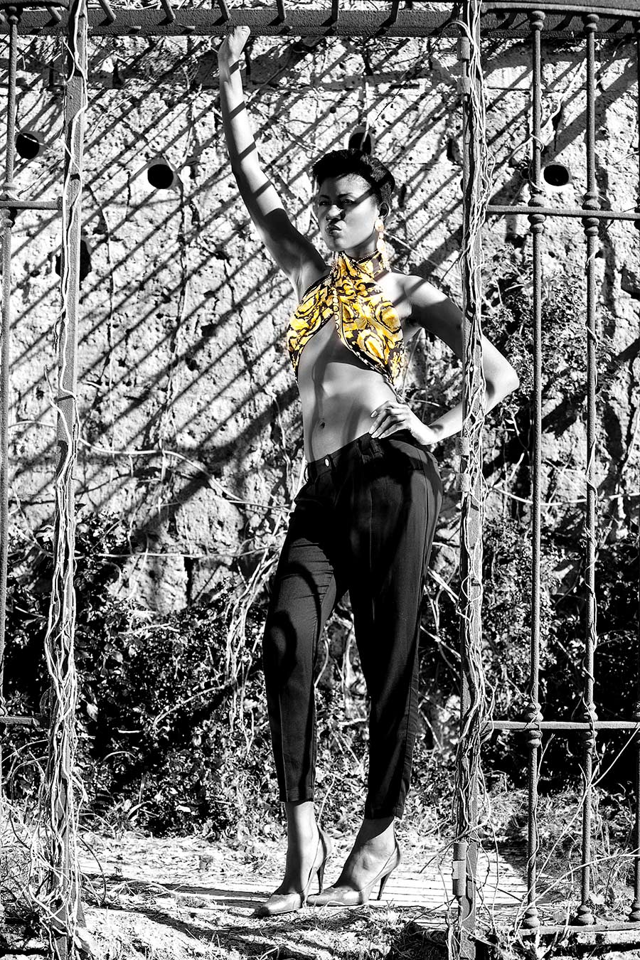 Modella in piedi ritratta in bianco e nero, indossa un top incrociato giallo - Dialoghi / Dissing - Gianni Versace Magna Grecia Tribute (photo©iTrancheseFotografi)