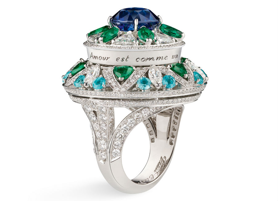 Van Cleef & Arpels - Collezione alta gioielleria Le Secret - Anello Fleur Bleue - Oro bianco, diamanti, smeraldi, tormaline Paraíba, uno zaffiro cuscino di 5,13 carati (Birmania). Ad una prima occhiata l’anello ci colpisce per l’importante zaffiro blu, con un tocco discreto ed una rotazione di un quarto di giro, scopriamo poi che il gioiello svela il tratto poetico di Oscar Wilde che cita l’amore paragonandolo alla natura.