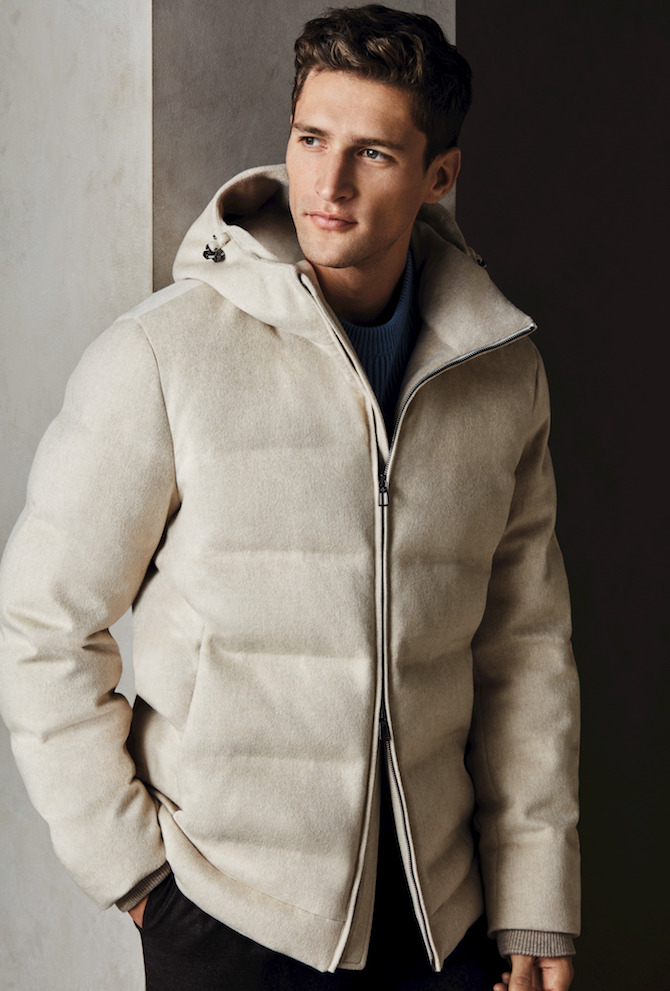 Piumino con cappuccio in white wheat mélange cashmere Storm System®. Maglione in cashmere a coste inglesi in soap azure. Pantaloni con coulisse a pince singola in flanella di lana e cashmere burnt brown. Piumino con cappuccio in white wheat mélange cashmere Storm System®. Maglione in cashmere a coste inglesi in soap azure. Pantaloni con coulisse a pince singola in flanella di lana e cashmere burnt brown.